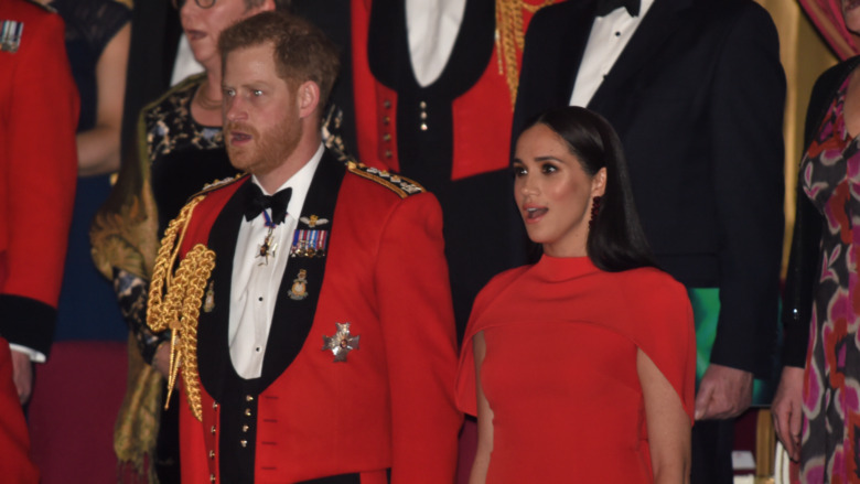 Le prince Harry et Meghan Markle debout avec la bouche ouverte