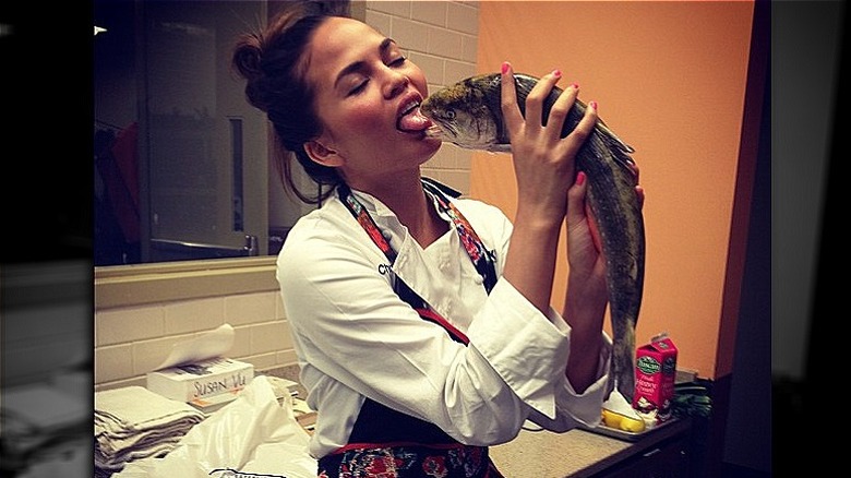 Chrissy Teigen faisant semblant d'embrasser un poisson