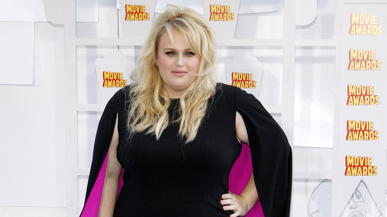 Rebel Wilson posant dans une robe noire sur un tapis rouge