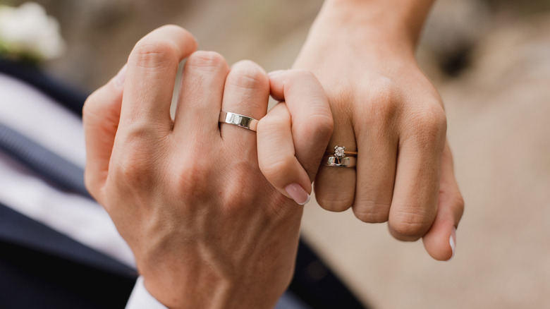 Les mains du couple marié, avec des pinkies entrelacés 