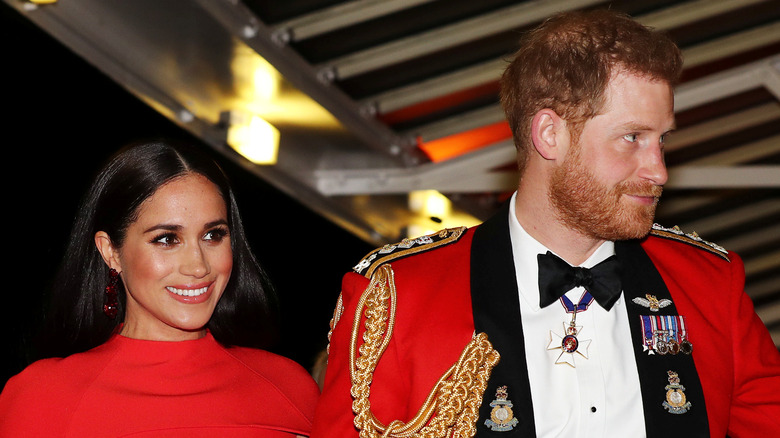 Meghan Markle et le prince Harry vêtus de rouge et souriant lors d'un événement