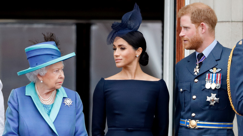 reine elizabeth ii, meghan markle et prince harry debout côte à côte