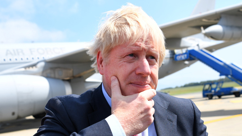 Boris Johnson devant l'avion, main au menton