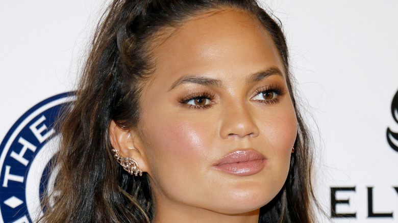 Chrissy Teigen sourit sur le tapis rouge