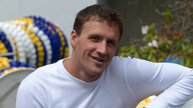 Ryan Lochte posant au bord de la piscine devant des diviseurs de voie