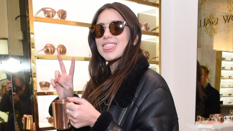 Dua Lipa souriant et jetant un signe de paix