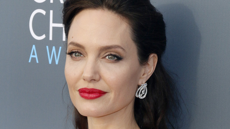 Angelina Jolie souriante en rouge à lèvres sur le tapis rouge