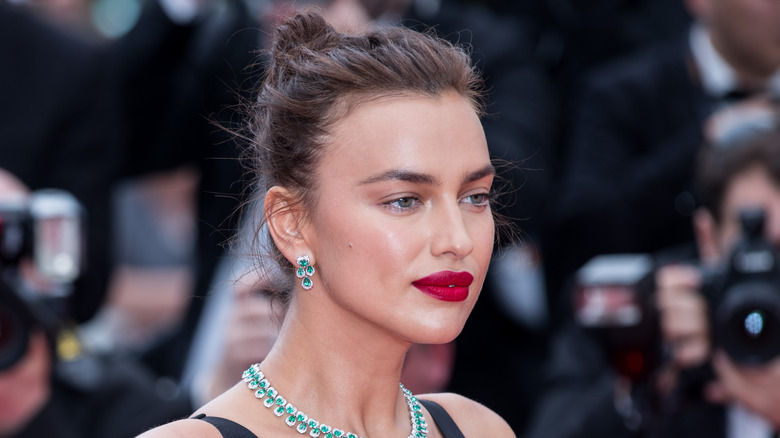 Irina Shayk pose en rouge à lèvres et tenue noire.