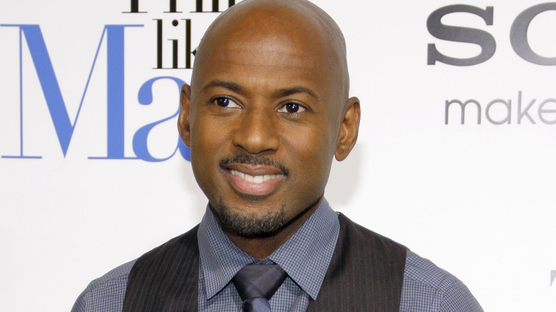 Romany Malco souriant dans un gilet et une cravate