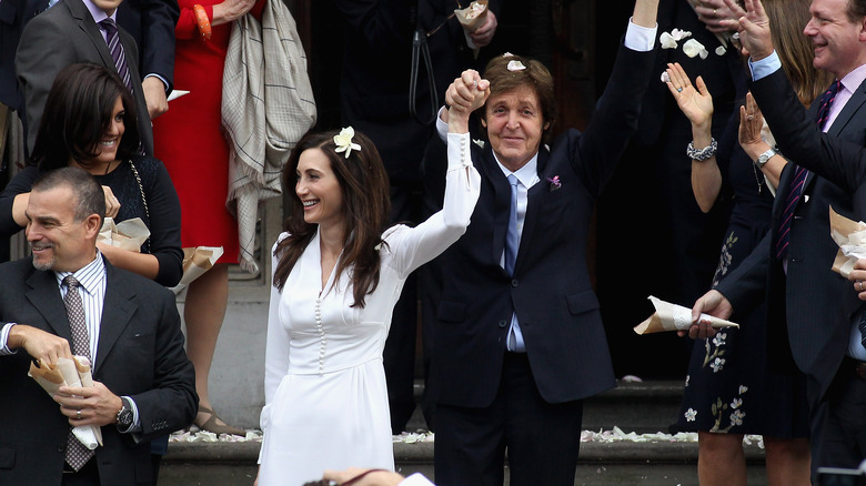 Paul McCartney et Nancy Shevell, tous deux souriants les mains en l'air