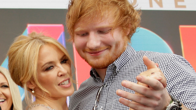 Kylie Minogue et Ed Sheeran se tenant la main