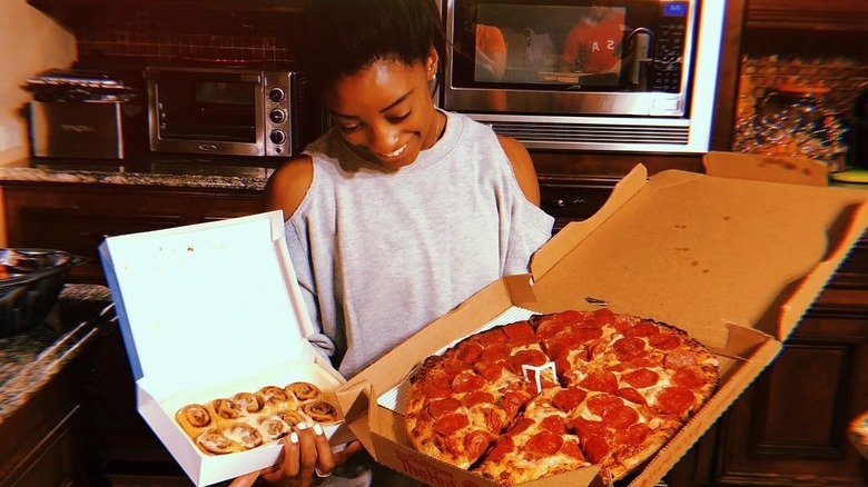 Simone Biles souriant à la pizza