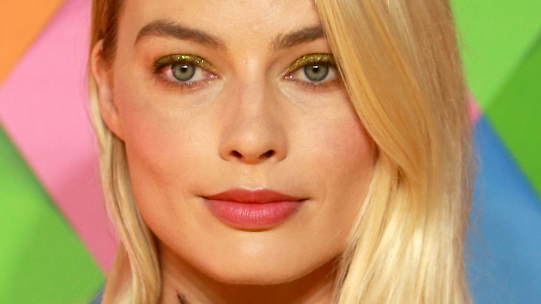 Margot Robbie avec un léger sourire et un rouge à lèvres rose