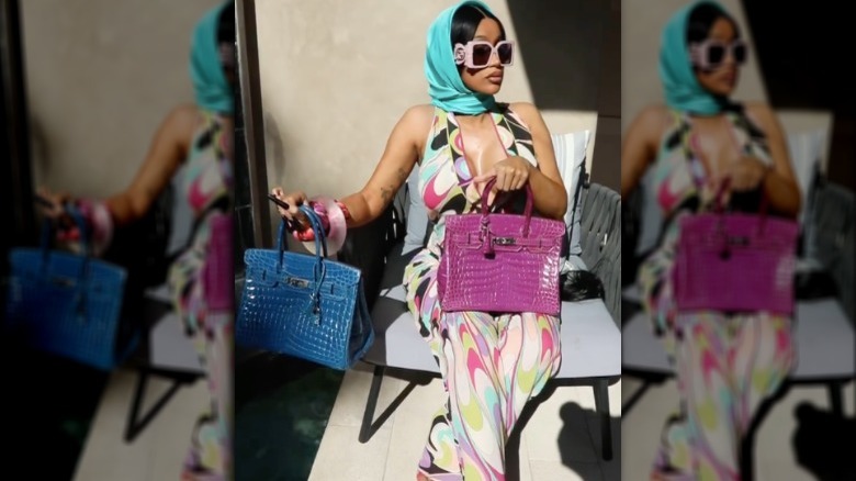 Cardi B posant avec deux de ses sacs Hermés Birkin. 