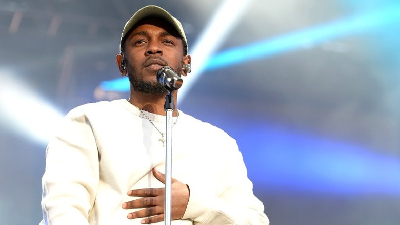 Kendrick Lamar s'exprimant au micro portant un sweat-shirt blanc