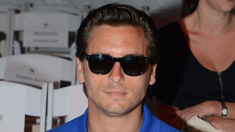 Scott Disick souriant avec des lunettes de soleil