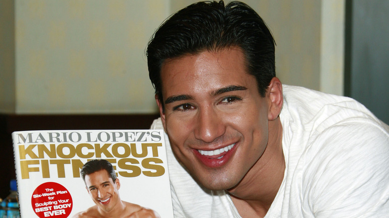 Mario Lopez souriant avec son livre de fitness