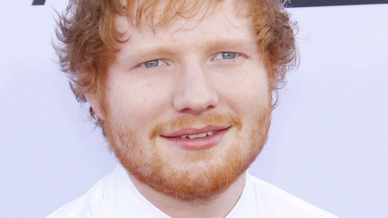 Ed Sheeran souriant et regardant sur le côté