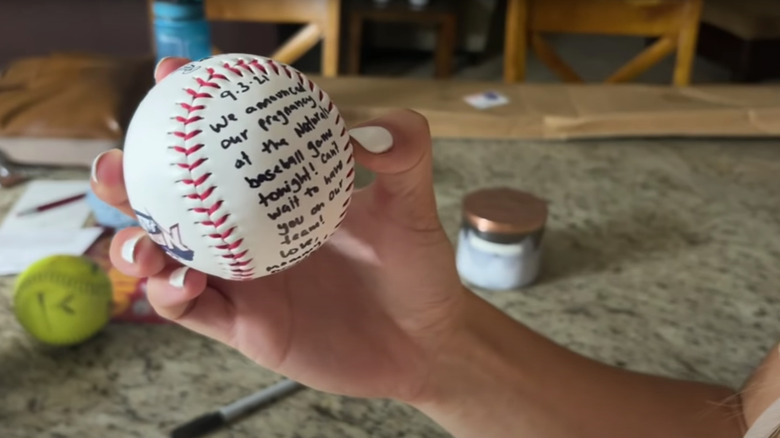 Katey Nakatsu tenant une balle de baseball avec une annonce de grossesse
