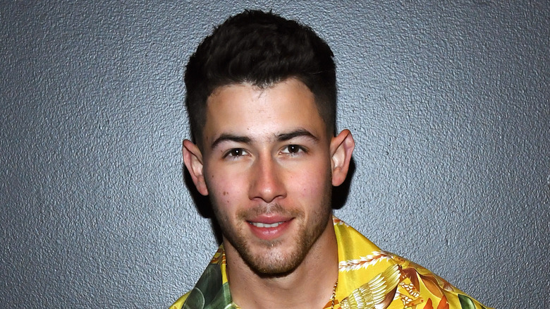 Nick Jonas sourit devant un fond noir