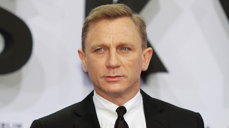 Daniel Craig avec une expression sérieuse portant un costume sur le tapis rouge