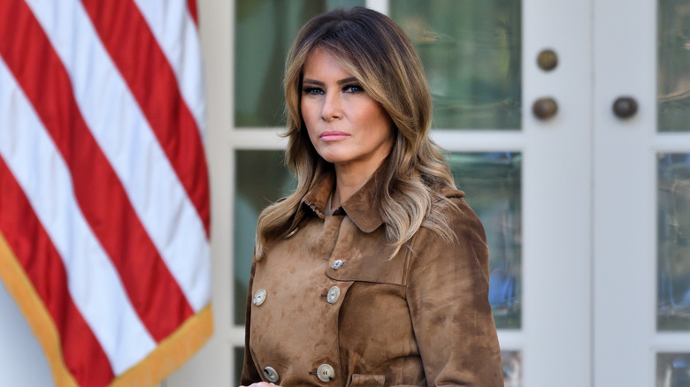 Melania Trump debout devant la Maison Blanche avec une expression sérieuse