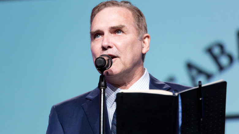 Norm Macdonald tenant un livre en parlant