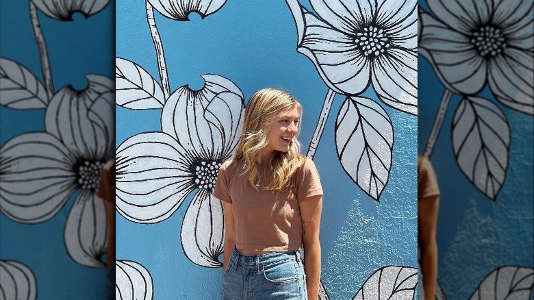 Gabby Petito souriant avec une fresque florale en arrière-plan