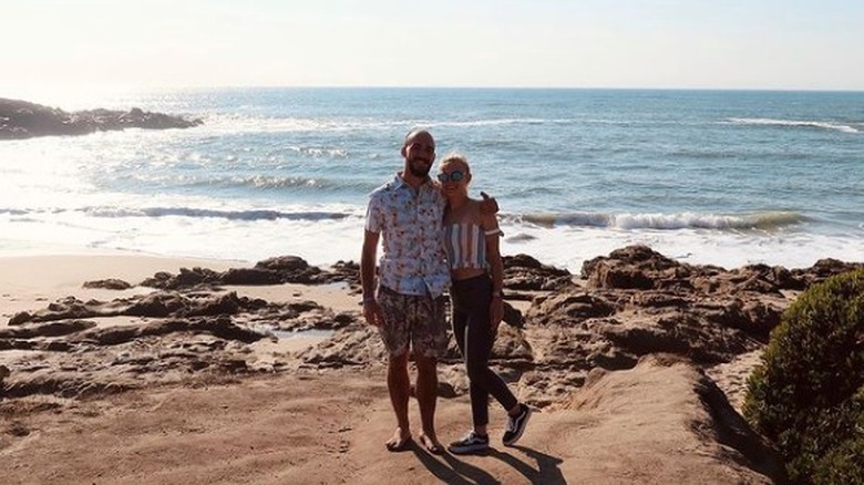 Brian Laundrie et Gabby Petito souriant avec de l'eau en arrière-plan