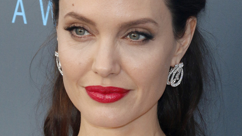 Angelina Jolie avec du rouge à lèvres et un léger sourire sur le tapis rouge