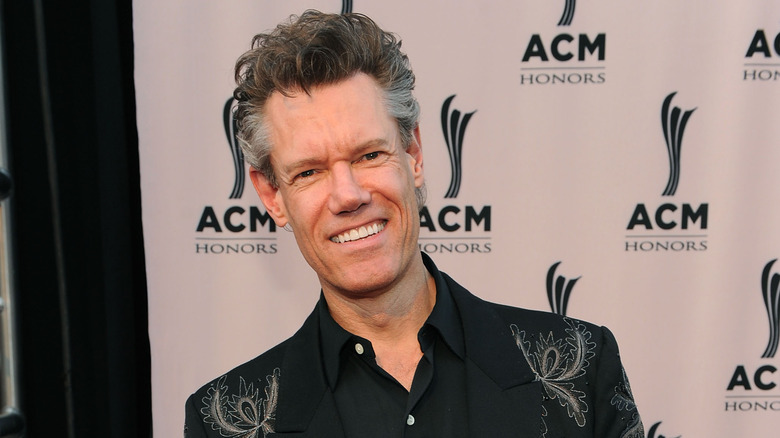 Randy Travis pose dans une tenue sombre en 2010.