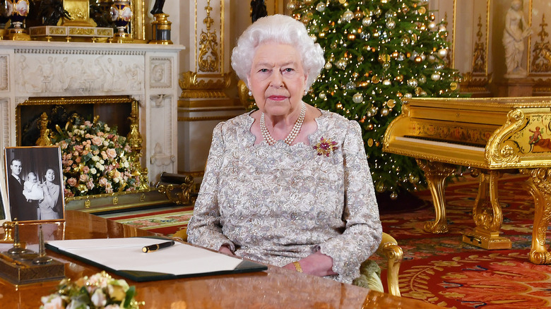 La reine Elizabeth II assise à un bureau