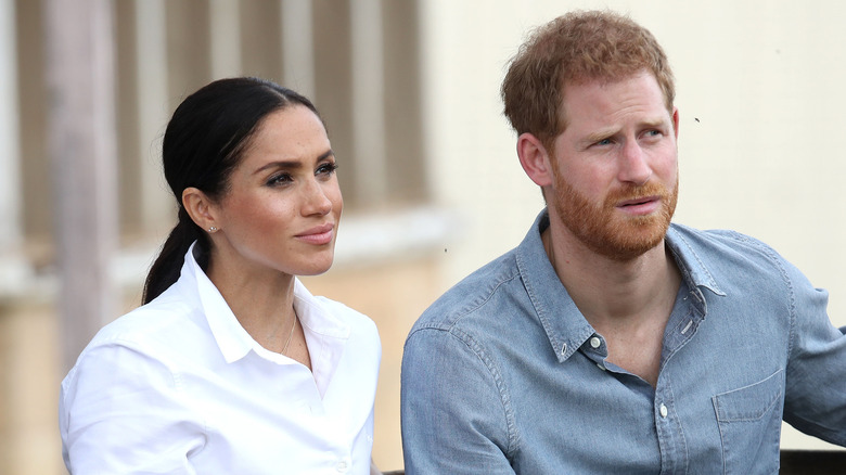 Meghan Markle et le prince Harry avec des expressions sérieuses.