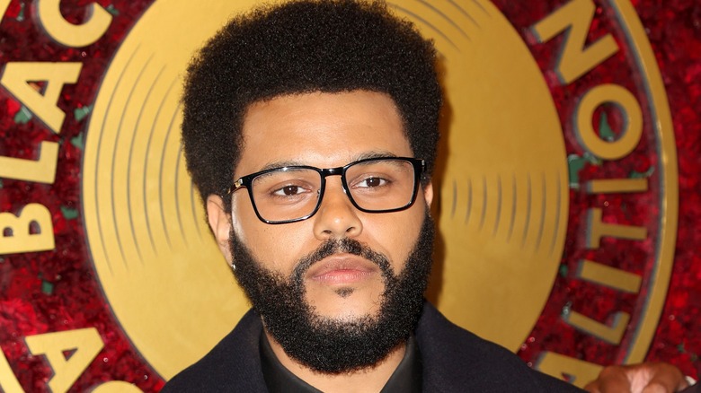 The Weeknd porte des lunettes à monture noire en posant pour une photo