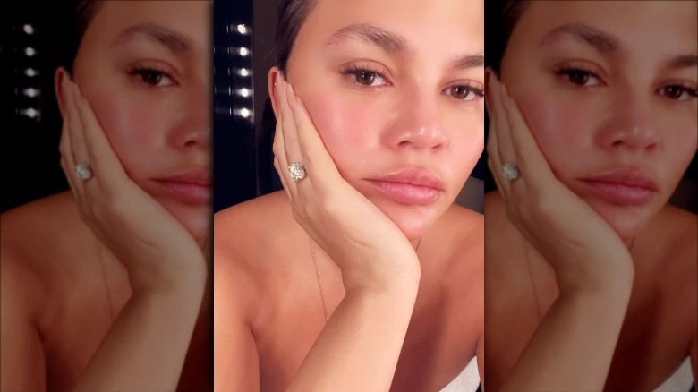 Chrissy Teigen avec la main sur son visage