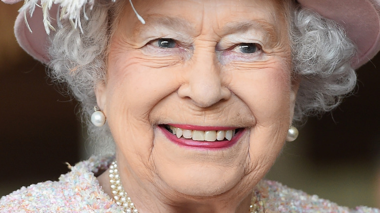 La reine Elizabeth II sourit dans un chapeau rose