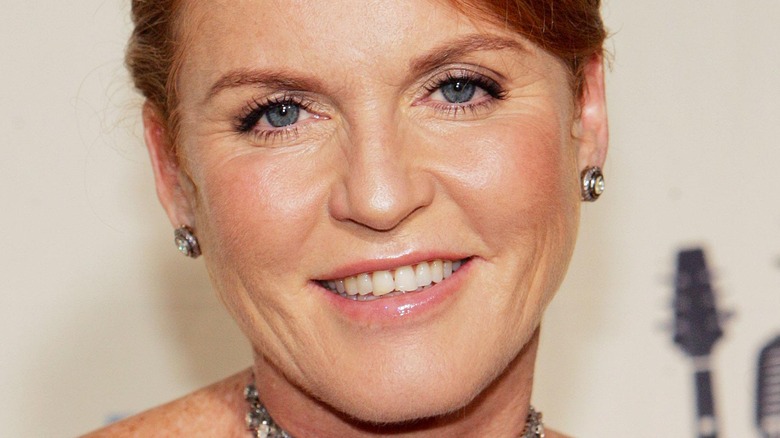 Sarah Ferguson sourit avec des boucles d'oreilles et un collier.