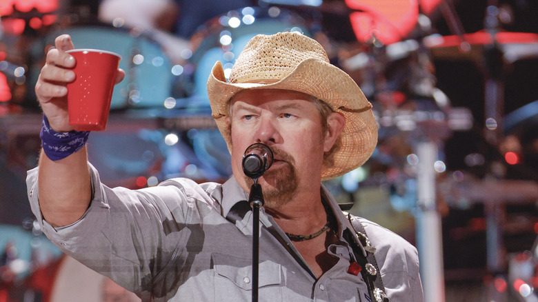 Toby Keith levant une tasse rouge pendant un concert 