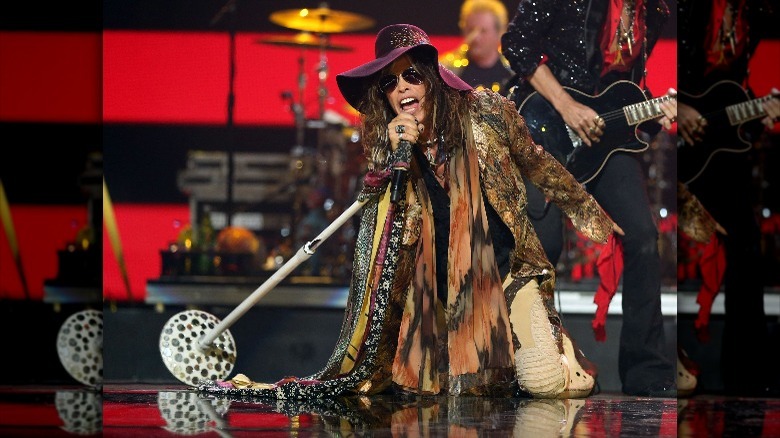 Steven Tyler se produit avec un chapeau violet et beaucoup d'écharpes