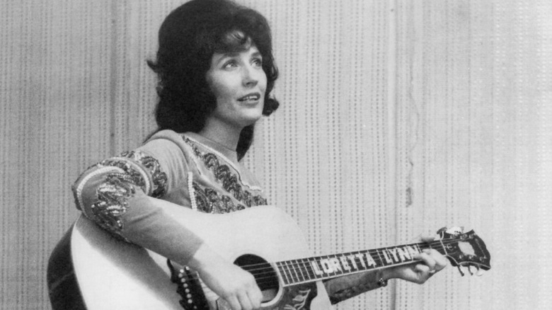 Loretta Lynn joue de sa guitare avec une expression réfléchie, 1965