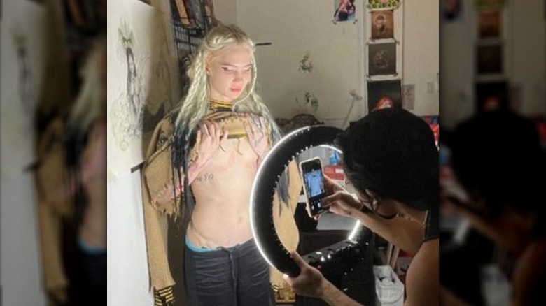 Grimes montrant son tatouage sur la poitrine