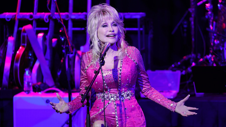 Dolly Parton chante dans une robe rose vif sur scène