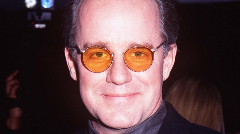 Phil Hartman avec des lunettes, souriant doucement