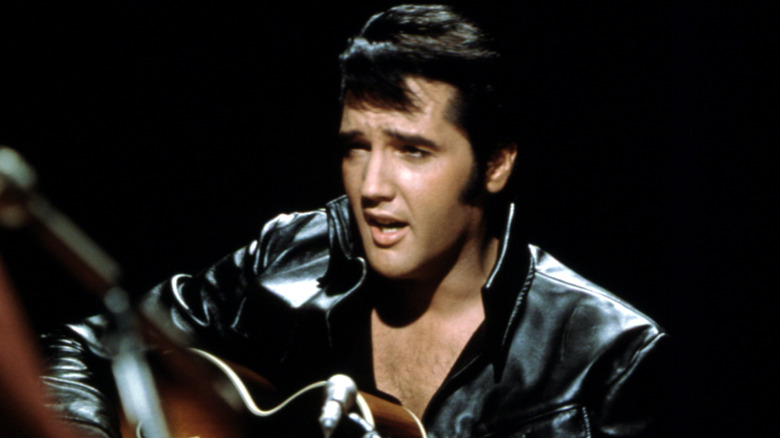 Elvis Presley porte une veste en cuir noire lors d'un concert