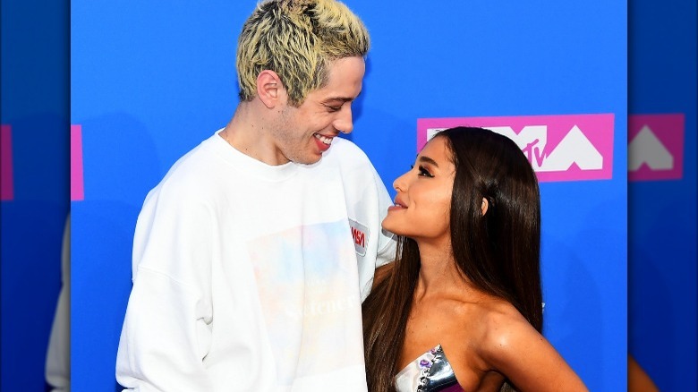 Pete Davidson regarde Ariana Grande, tous deux souriants