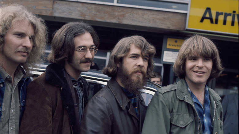 Des membres de Credence Clearwater Revival posent près d'une voiture