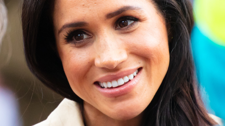 Meghan Markle souriant par-dessus son épaule