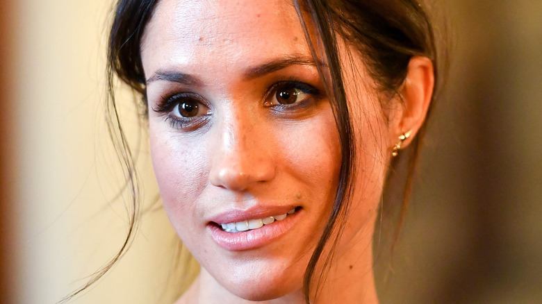 Meghan Markle avec un chignon en désordre et des cheveux autour du visage