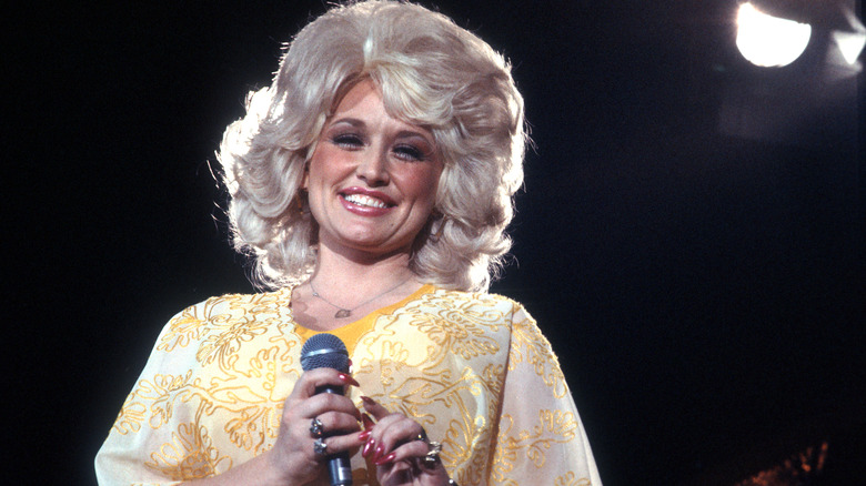 Dolly Parton souriant sur scène dans une tenue jaune flashy