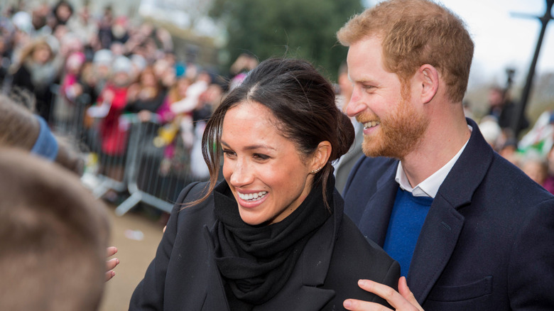 Le prince Harry rit derrière Meghan Markle